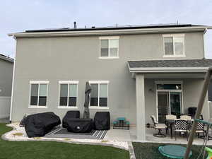 Back of property featuring a patio, solar panels, stucco siding, and outdoor dining area/patio