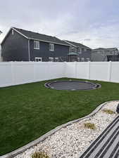 Fenced backyard featuring a trampoline