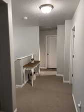 Hallway with light carpet and a textured ceiling