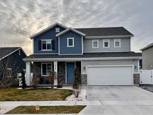 Traditional-style home featuring a porch, stone siding, concrete driveway, and an attached garage