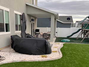 Fenced yard with a playground and a patio area