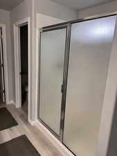 Master bathroom with light wood-style floors and a shower stall