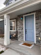 Property entrance featuring stone siding and a porch