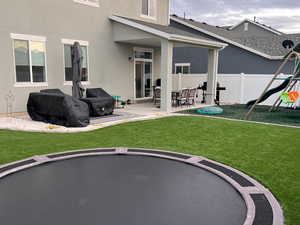 Back of property featuring a patio area, a trampoline, stucco siding, and a playground