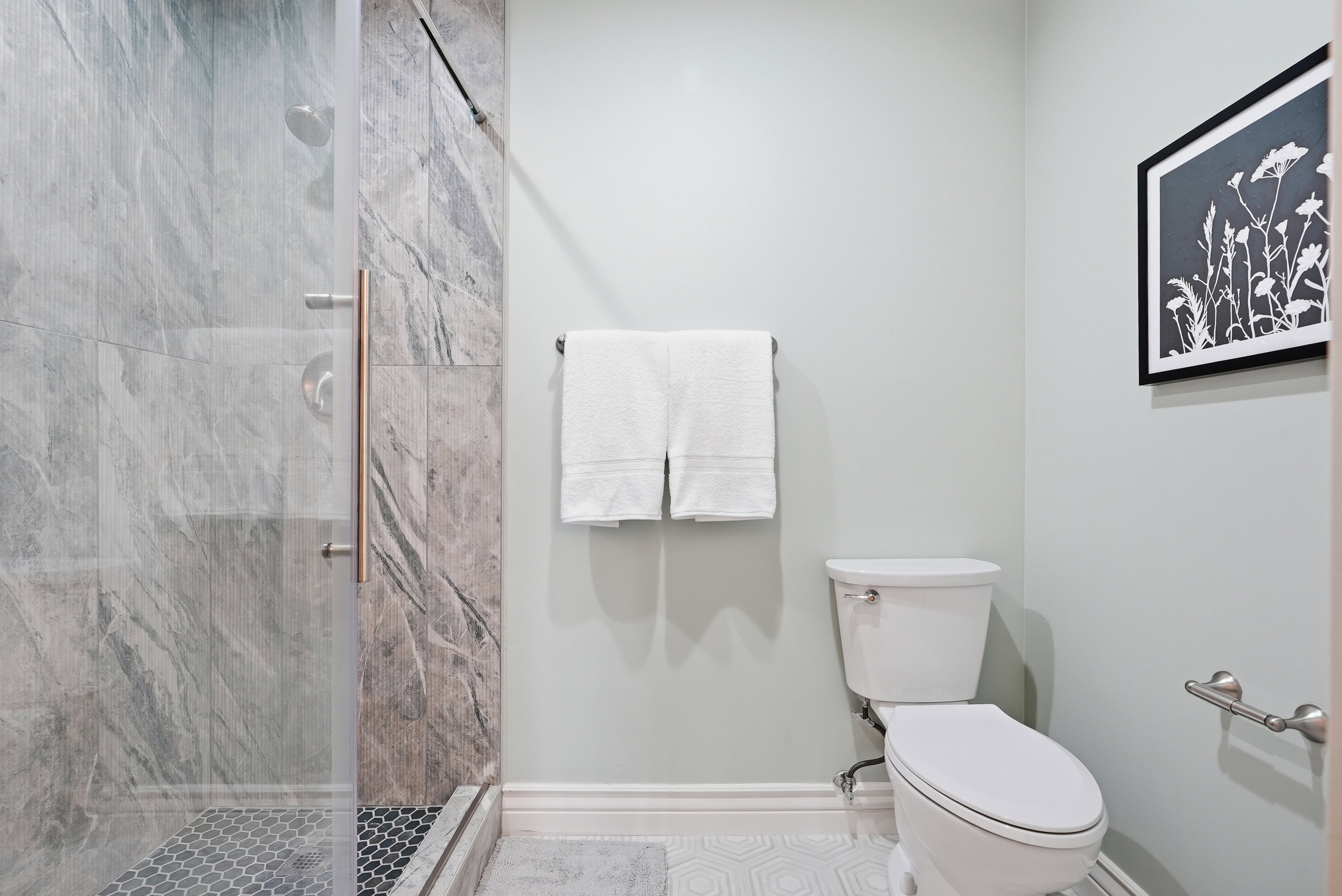 Full bathroom featuring toilet and a marble finish shower