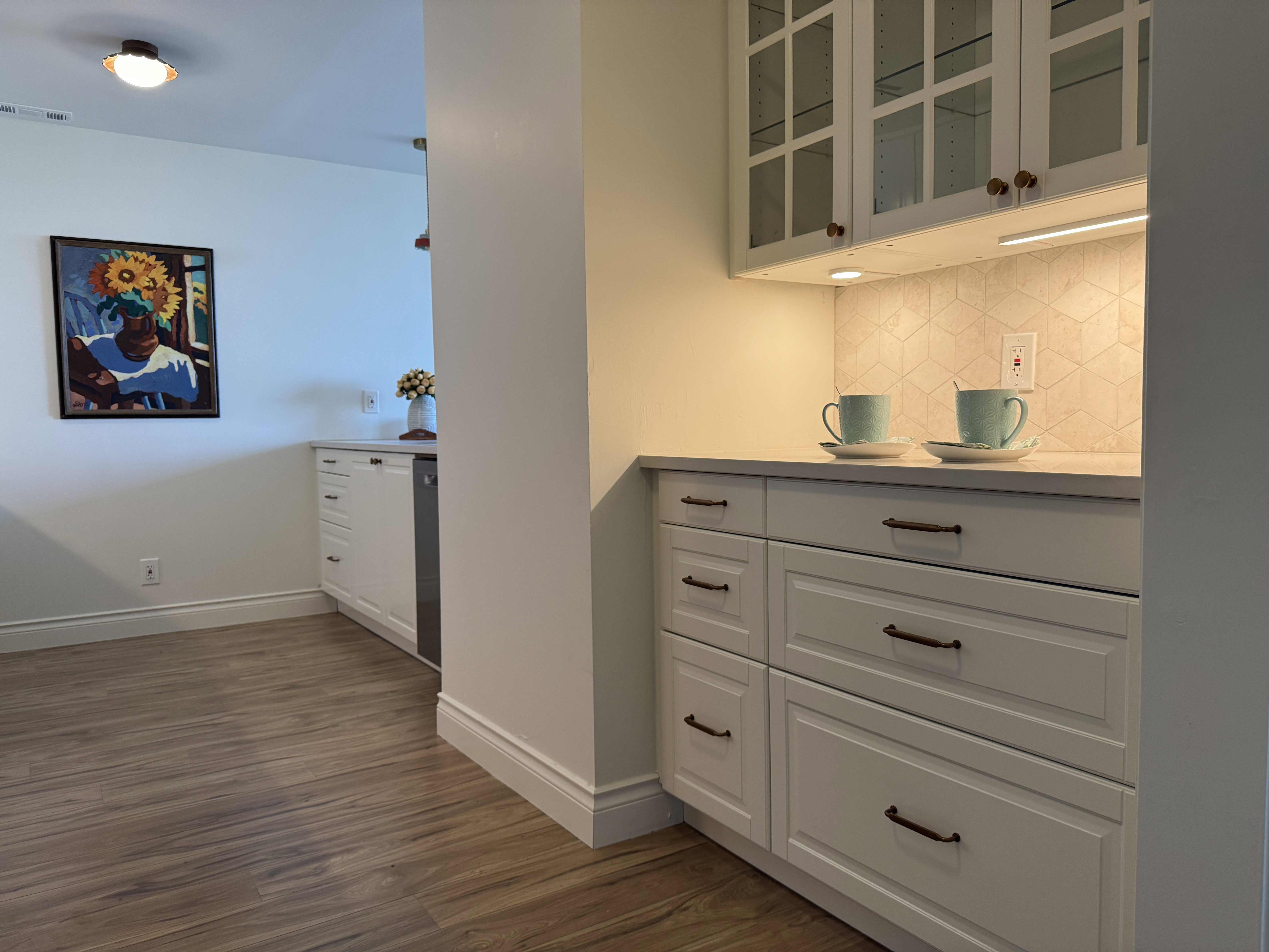 Built-in cabinetry featuring glass-front uppers, under-cabinet lighting, and a geometric tile backsplash