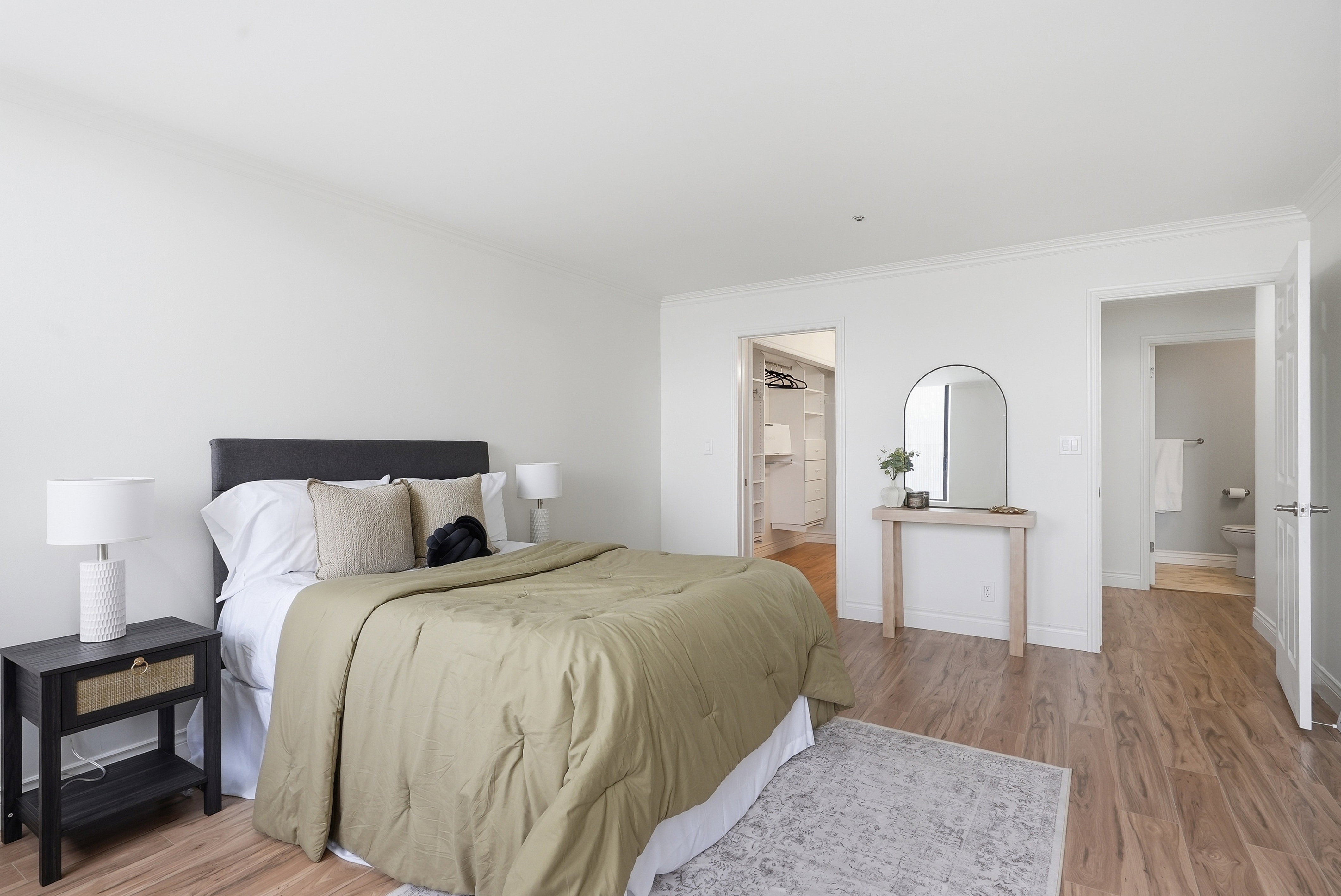 Bedroom with light wood-style floors, ornamental molding, and ensuite bath