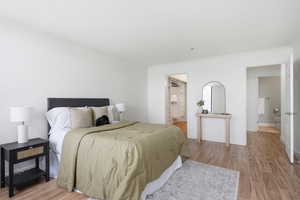 Bedroom with light wood-style floors, ornamental molding, and ensuite bath