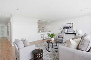 Living area with light wood-type flooring, ornamental molding, and recessed lighting