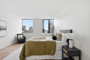 Bedroom featuring ornamental molding, light wood-style floors, recessed lighting, and a view of city