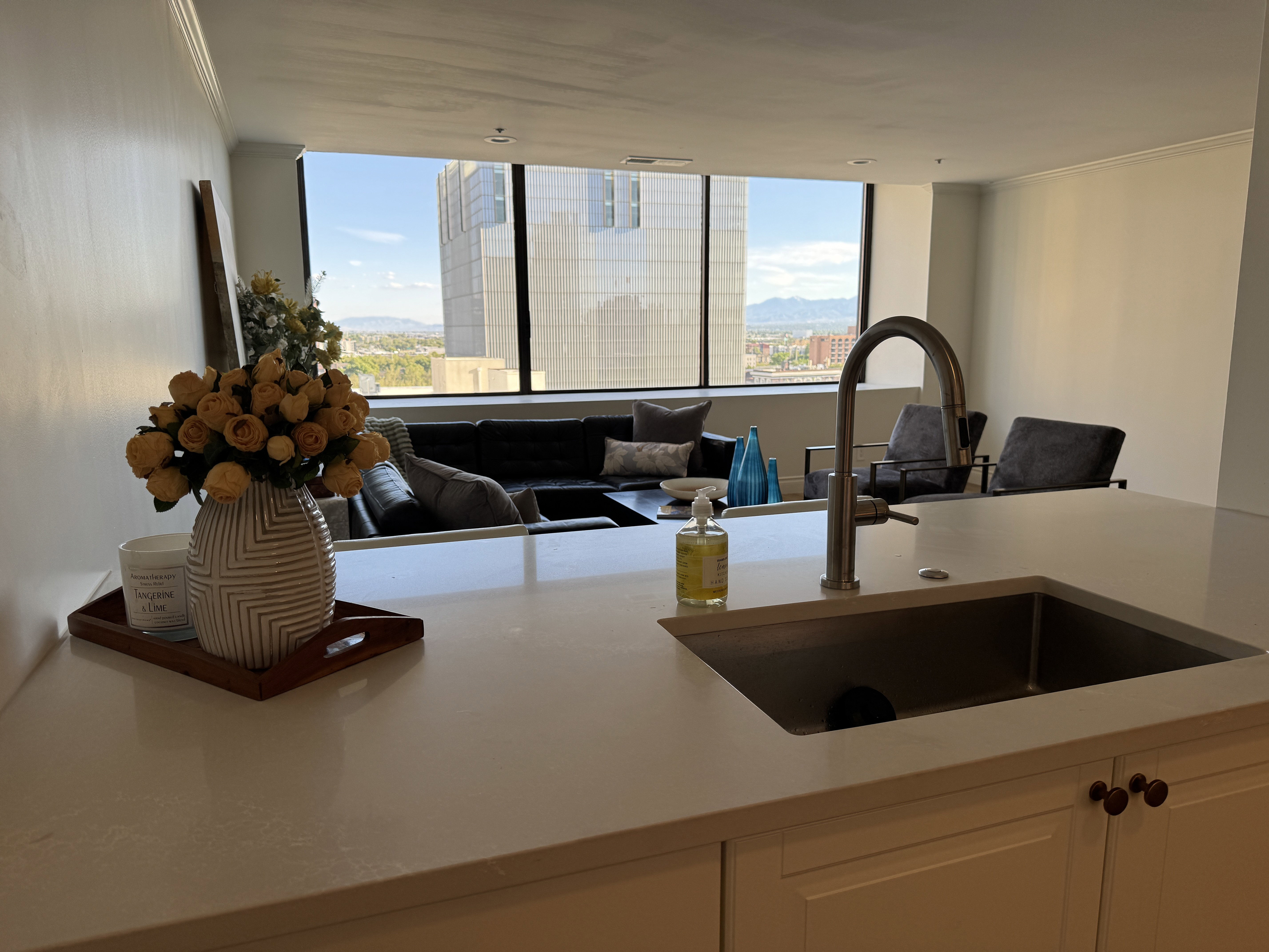 Kitchen island with a light-toned countertop, integrated stainless steel sink, and a gooseneck faucet