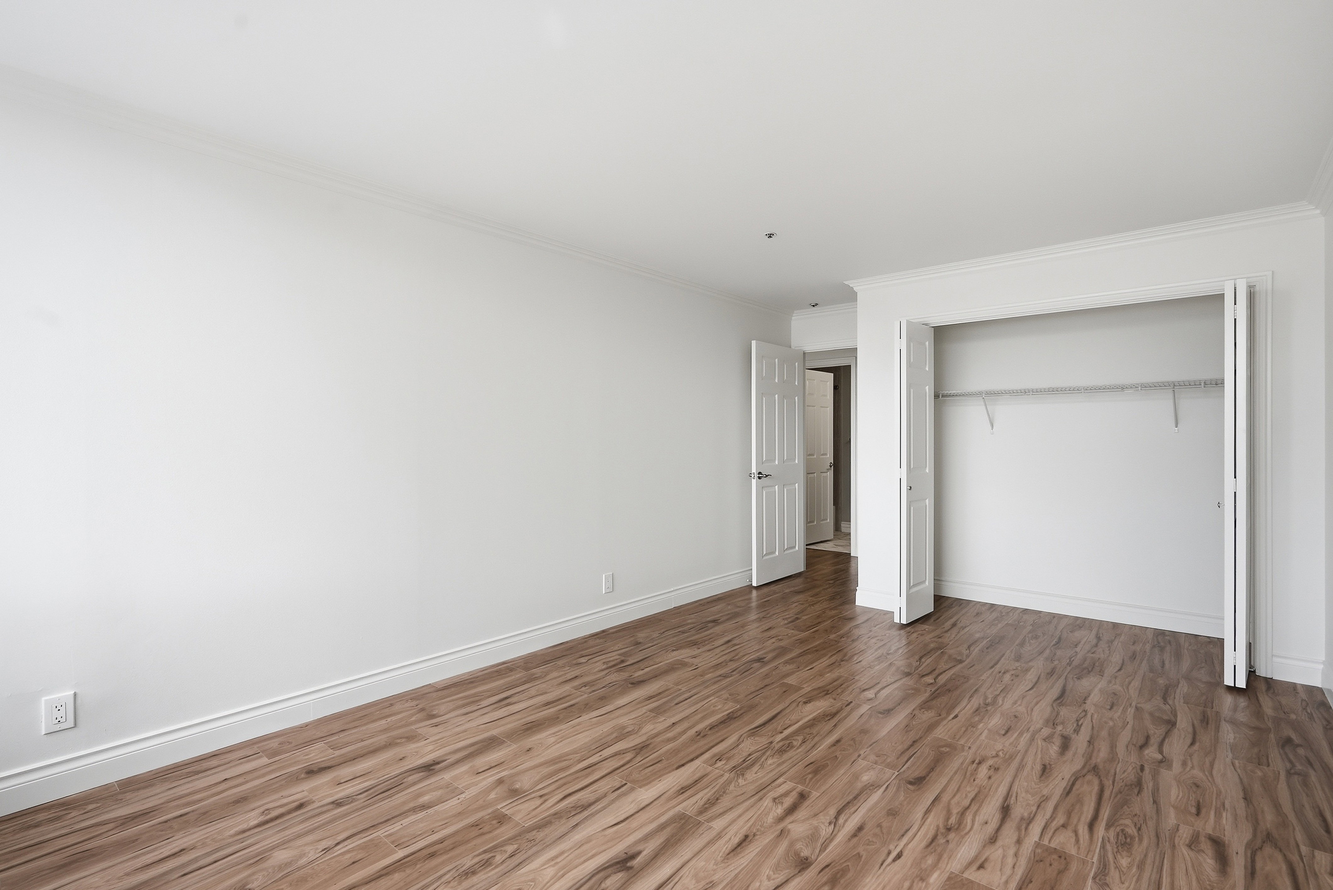 Unfurnished bedroom featuring a closet, dark wood-style floors, and ornamental molding