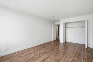 Unfurnished bedroom featuring a closet, dark wood-style floors, and ornamental molding
