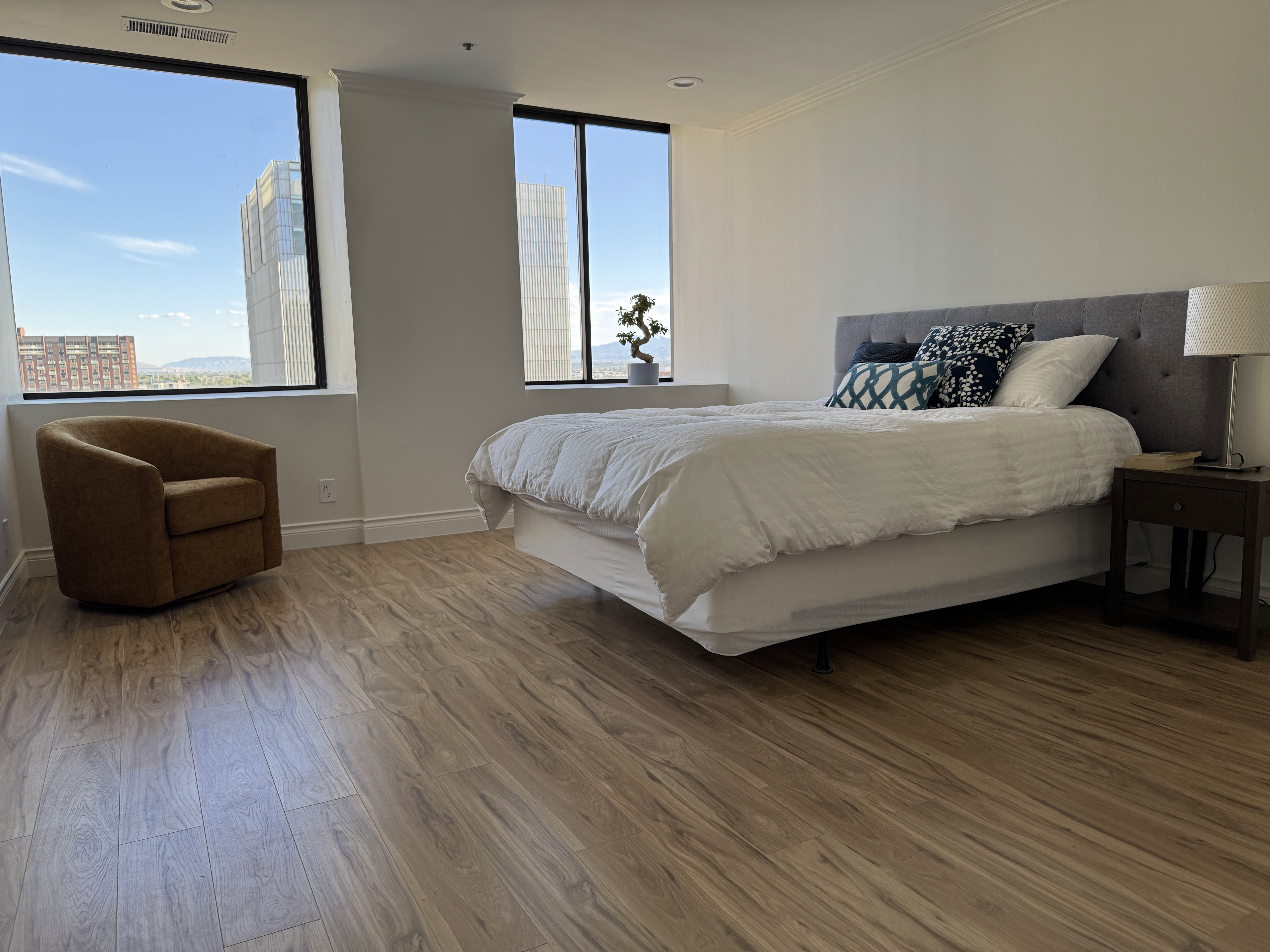 Expansive room featuring wood-finish flooring, white baseboards, and crown molding