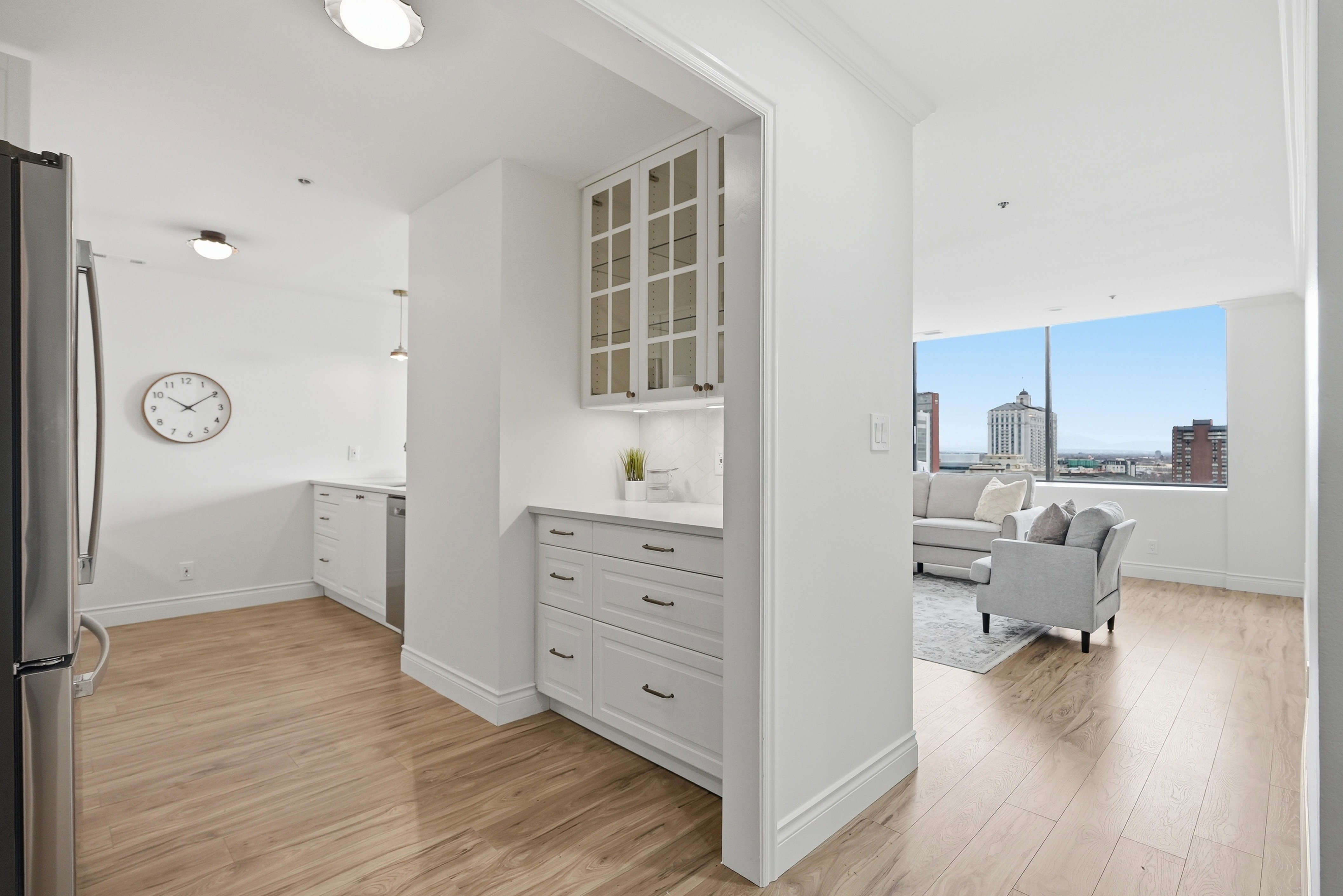 Kitchen featuring glass fronted cabinets, white cabinets, light wood-style floors, and freestanding refrigerator