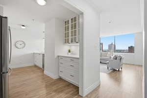 Kitchen featuring glass fronted cabinets, white cabinets, light wood-style floors, and freestanding refrigerator
