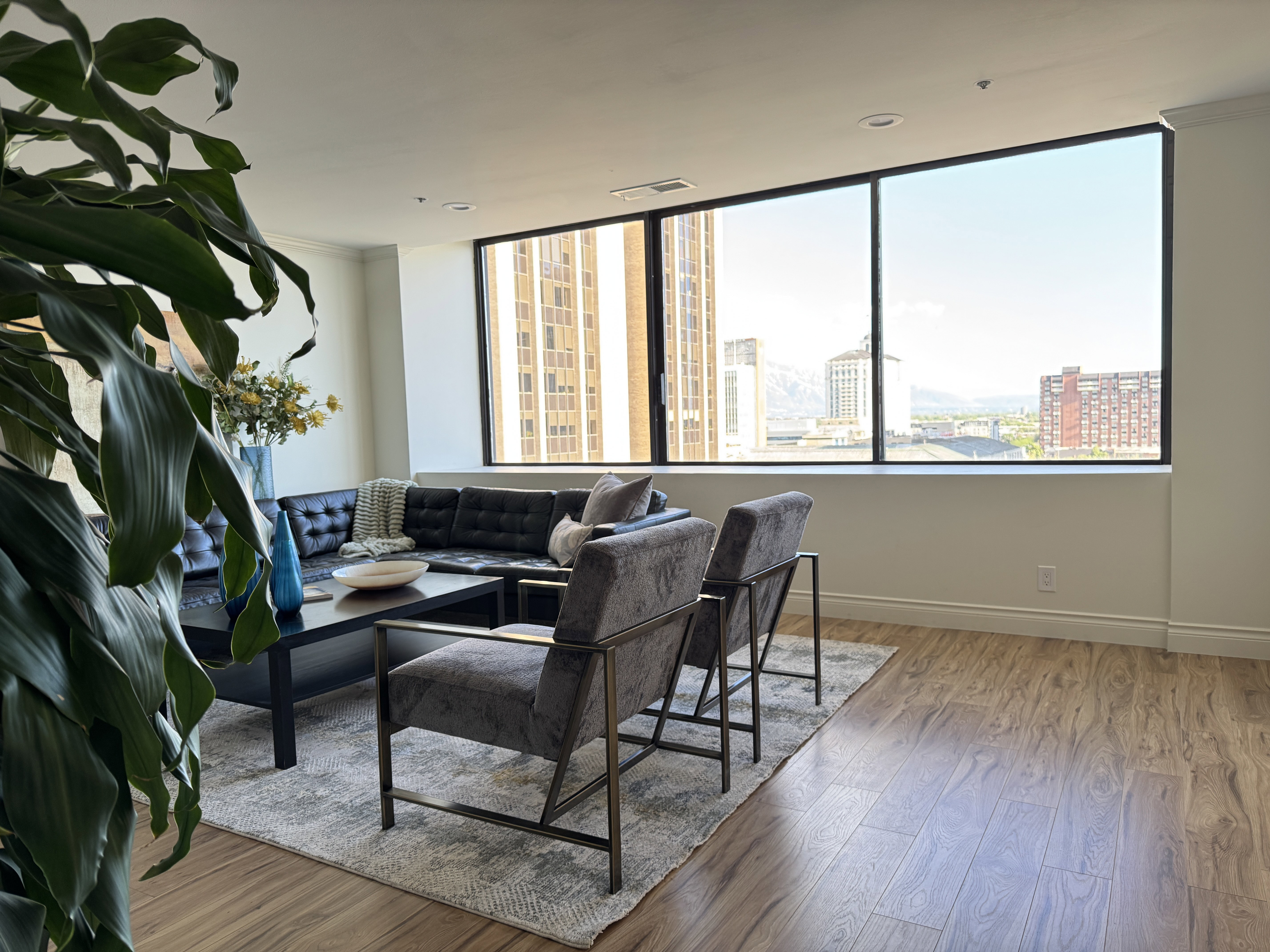 Floor-to-ceiling windows with expansive city and mountain scenery, wood-finish flooring, recessed lighting, and a neutral wall palette