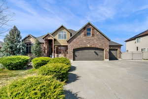 View of front of property with concrete driveway, a garage, brick siding, and stone siding
