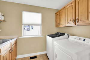 Laundry room with cabinet space, separate washer and dryer, and light tile patterned floors