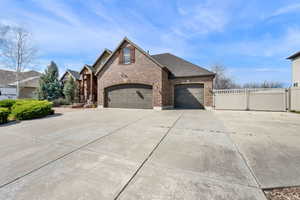 View of home's exterior with brick siding, driveway, a gate, an attached garage, and roof with shingles