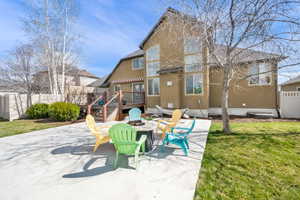 Back of house featuring a patio, a wooden deck, a fire pit, and stucco siding