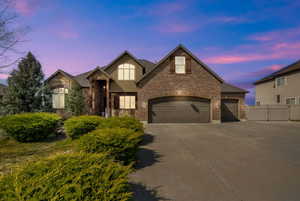 View of front of house with concrete driveway, stone siding, a garage, and brick siding