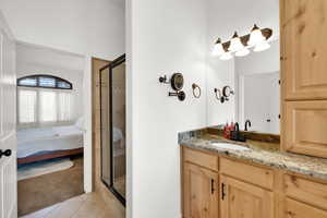 Ensuite bathroom with light colored carpet, vanity, a shower stall, and light tile patterned floors