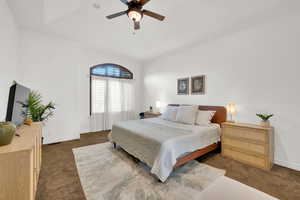Bedroom with dark carpet, a tray ceiling, and ceiling fan
