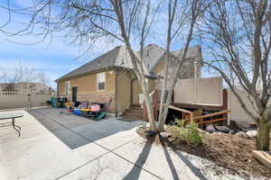 Back of house with stucco siding, a shingled roof, brick siding, and a patio