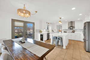 Dining area featuring light tile patterned flooring, a chandelier, and beverage cooler