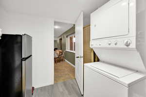 Laundry area featuring stacked washing machine and dryer and light wood-type flooring