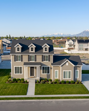 Contemporary two-story residence featuring dormer windows, dark asphalt shingles, and a covered porch entry