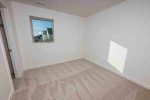 Unfurnished bedroom with light colored carpet and baseboards