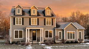 View of front of house featuring a shingled roof and covered porch