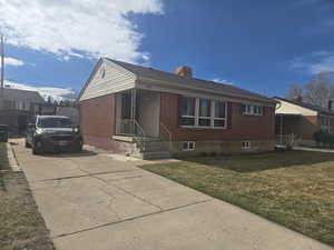 View of front of property featuring brick siding, concrete driveway, and a front yard