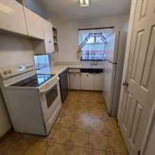 Kitchen with white appliances, light countertops, open shelves, and white cabinets