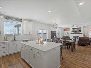 Kitchen with open floor plan, a center island, white cabinetry, a lit fireplace, and a kitchen breakfast bar