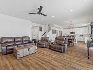 Living room featuring light wood-type flooring, a ceiling fan, and hanging lights
