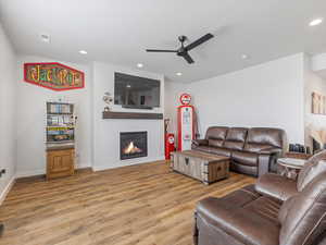 Living area featuring a glass covered fireplace, light wood-type flooring, ceiling fan, and recessed lighting