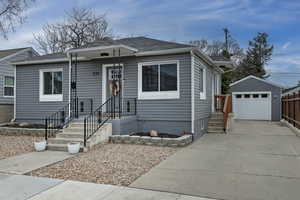 View of front of house with an outdoor structure, concrete driveway, a garage, and roof with shingles