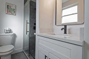 Full bath featuring vanity, a shower stall, and dark tile patterned flooring