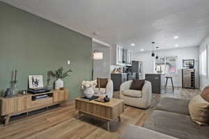 Living area with light wood-style flooring, a textured ceiling, and recessed lighting