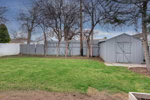 Fenced backyard featuring a shed