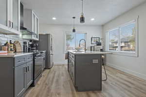 Dual tone kitchen featuring glass fronted cabinets, a breakfast bar area, electric range, hanging light fixtures, and an island with sink
