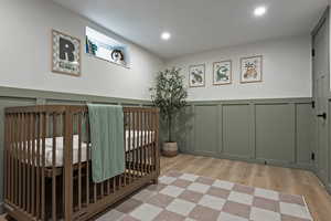 Corridor with a wainscoted wall, light wood-style flooring, a decorative wall, and recessed lighting