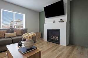 Living room featuring light wood-style floors, a lit fireplace, and a textured ceiling