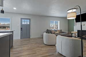 Living area featuring a textured ceiling, light wood-type flooring, a fireplace, and recessed lighting