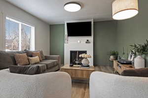 Living room featuring wood finished floors, a glass covered fireplace, and a textured ceiling