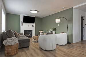 Living room with light wood-type flooring, a textured ceiling, and a fireplace