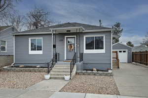 Bungalow with an outbuilding, a shingled roof, a garage, and driveway